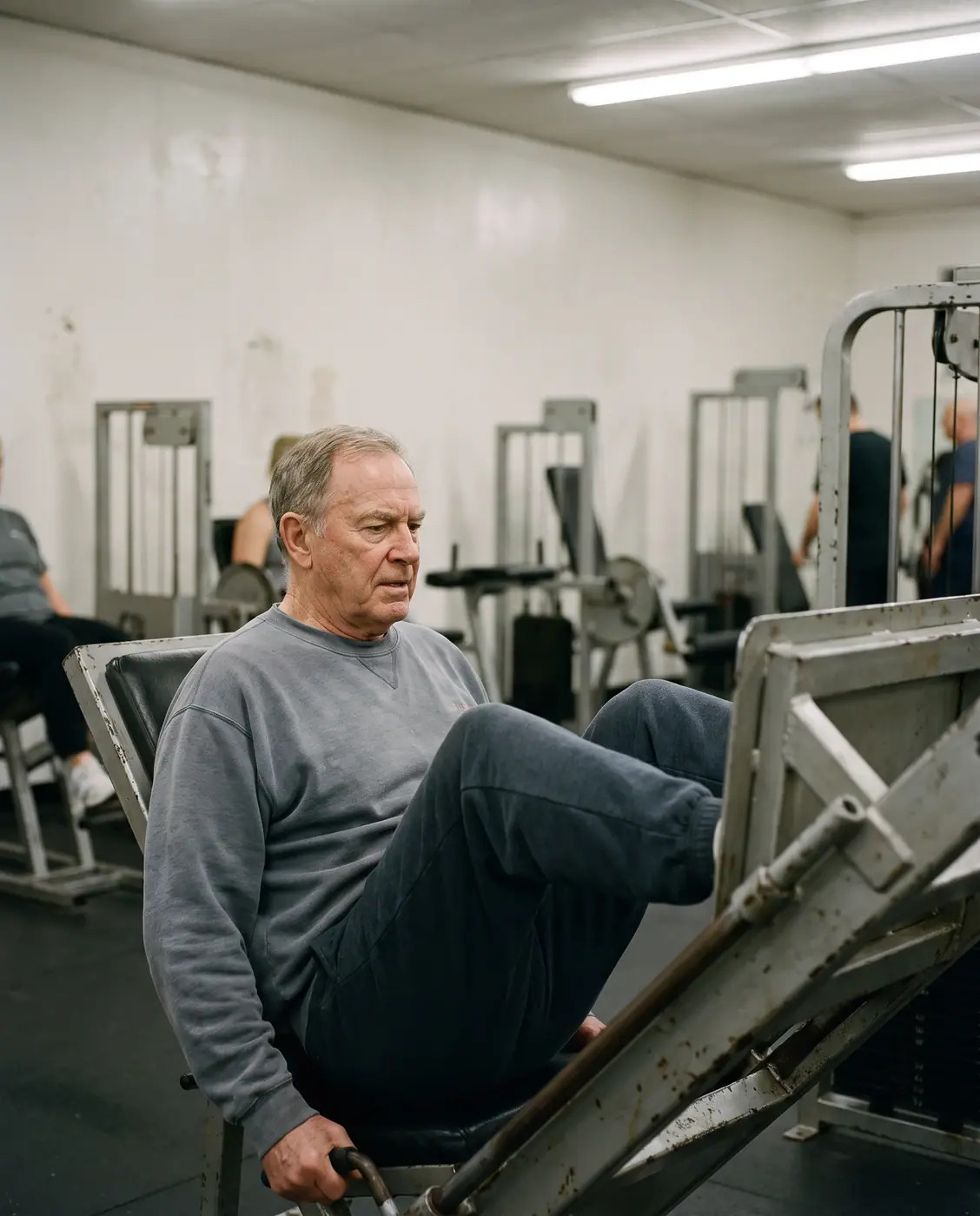 Dedicated senior man exercising his legs on a leg press machine in a well-lit, everyday