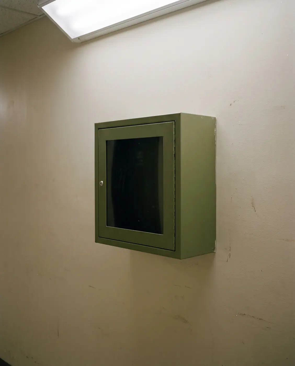 Wall mounted AED defibrillator cabinet green cross corridor