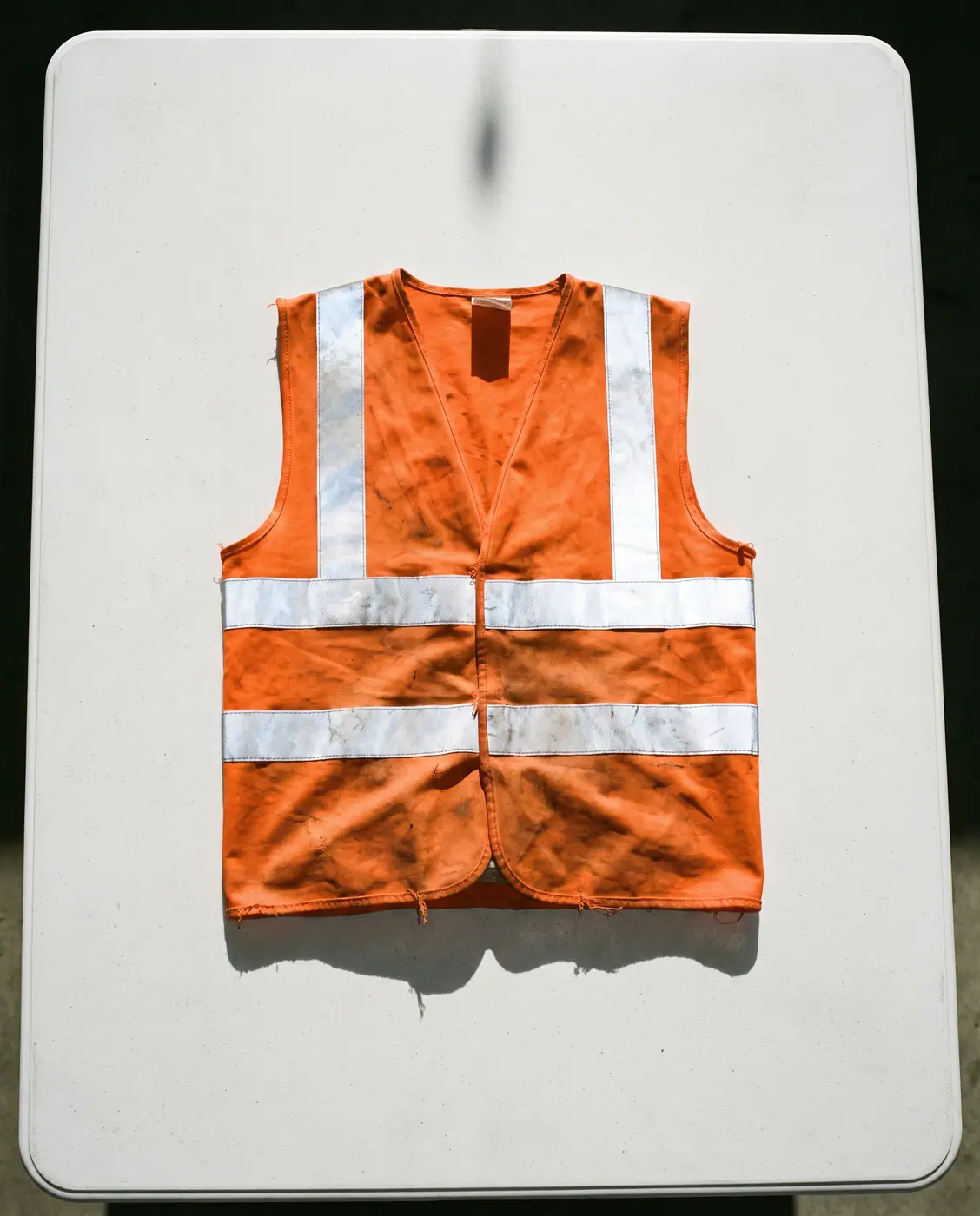 Orange high-visibility safety vest folded white surface isolated