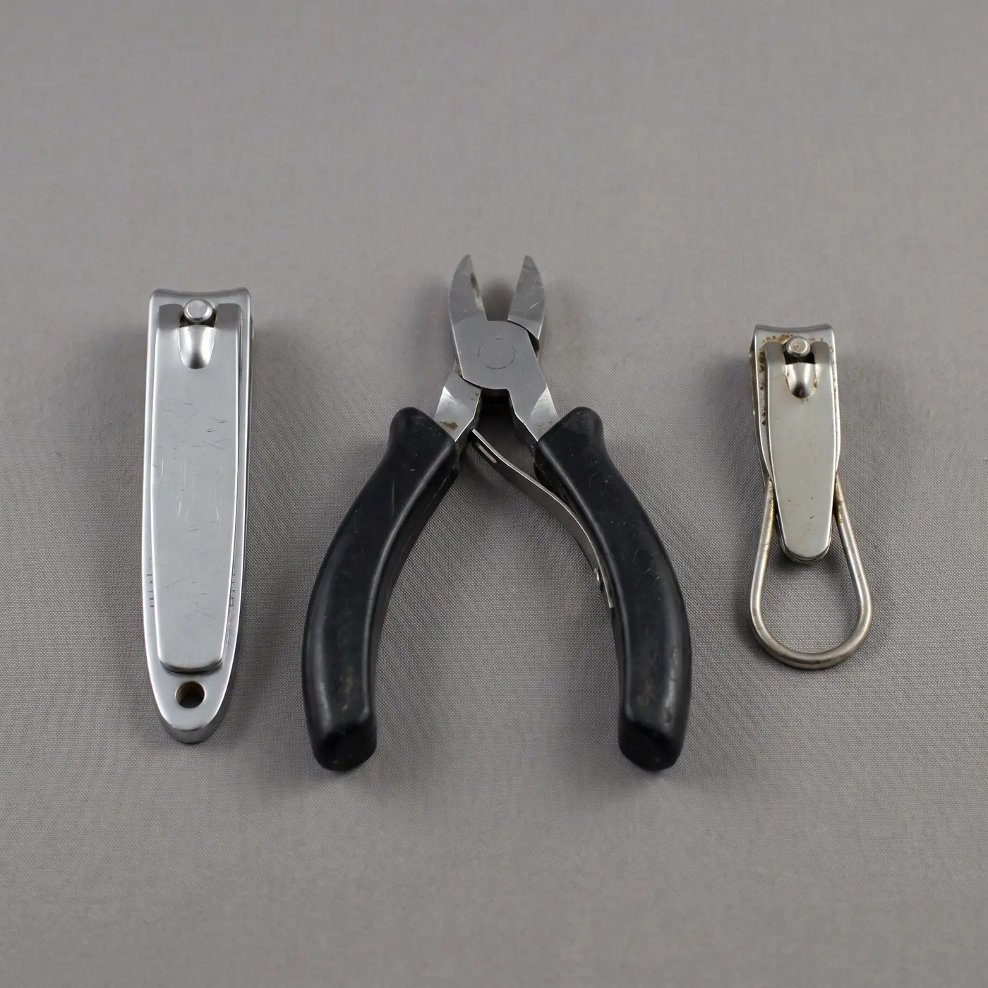 Three nail clippers variants side by side neutral background