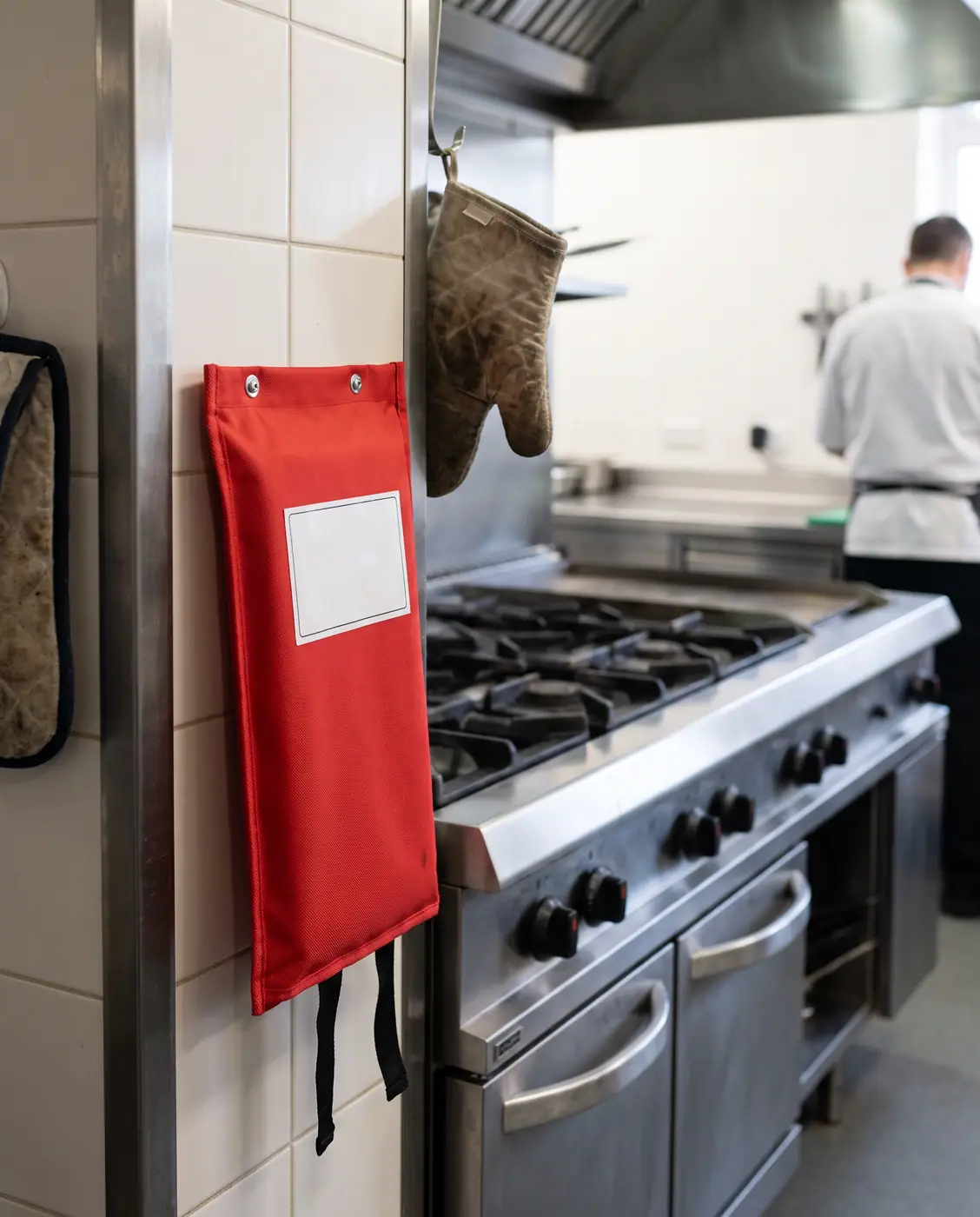 Fire blanket pouch mounted beside commercial kitchen range