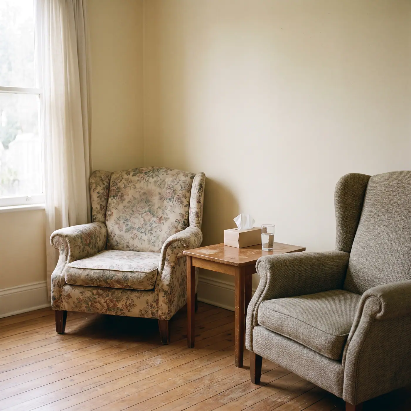 Warm counselling room with two armchairs, side table, tissues, and water, softly lit by