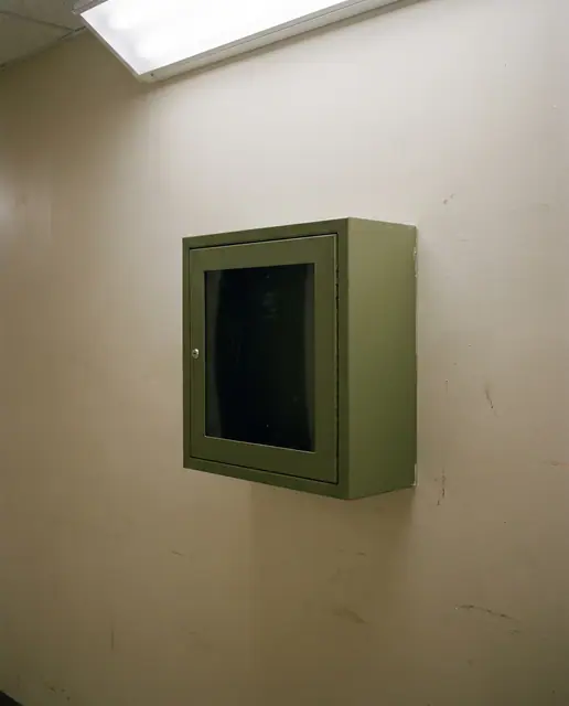 Wall mounted AED defibrillator cabinet green cross corridor