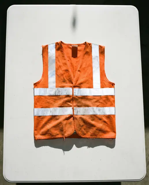 Orange high-visibility safety vest folded white surface isolated