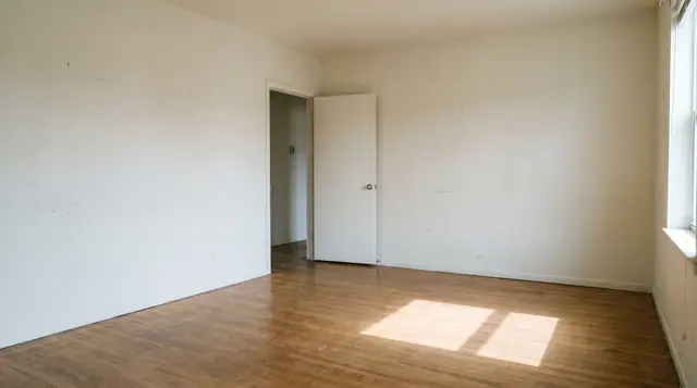 Empty modern room interior with a slightly open door, bare walls, and natural daylight