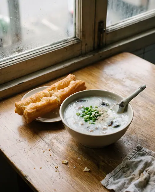 Traditional Cantonese century egg and pork congee with scallions, white pepper, and crispy