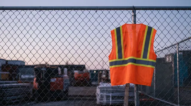 Reflective safety vest hanging construction fence hook morning light